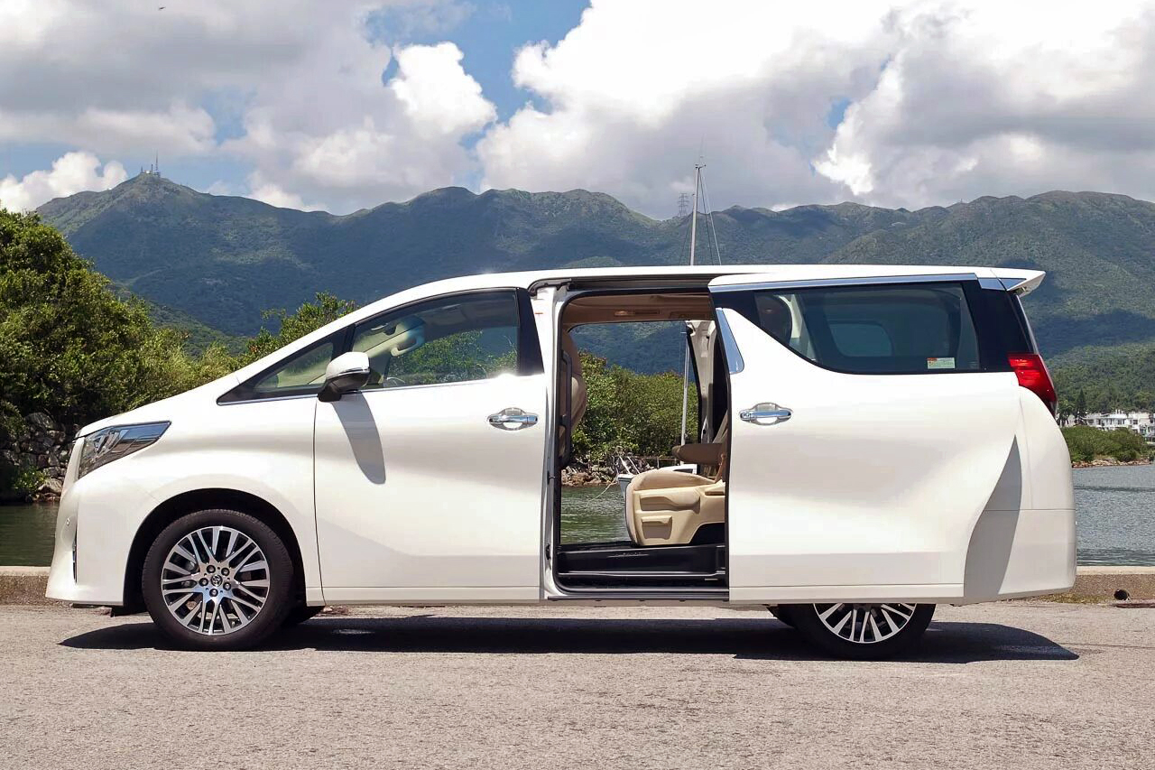 Mobil Toyota Alphard mewah sedang berjalan di jalanan Bali pada malam hari, Alt text: Sewa Alphard di Bali malam har